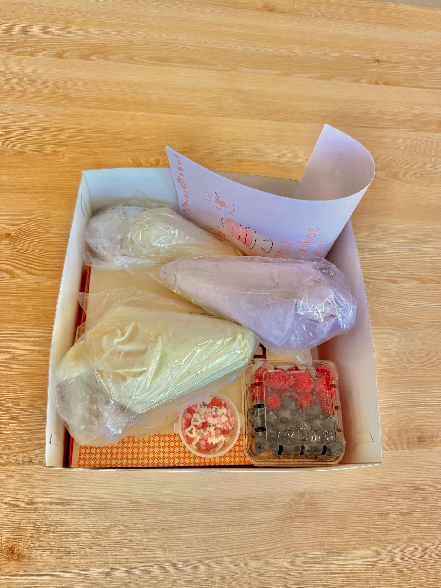 ingredientes del kit para hacer pastel: bizcochos, nata de colores y frutos rojos